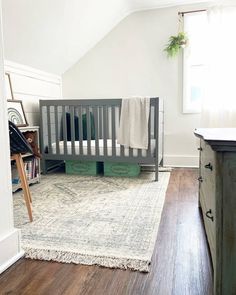 a baby crib in the corner of a room next to a dresser and window