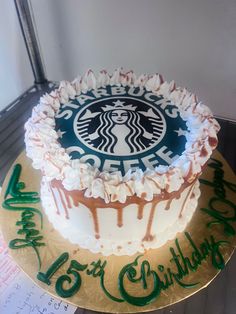 a starbucks cake with white frosting and green writing on the bottom is sitting on a gold plate