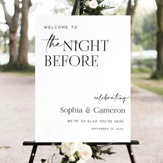 a welcome sign for the night before at an outdoor wedding ceremony with white flowers and greenery