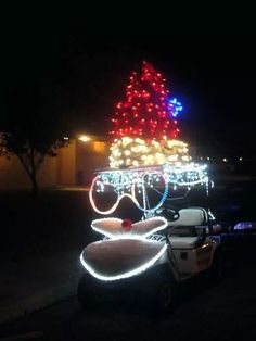 a golf cart with christmas lights on it and a tree lit up in the background