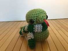 a small crocheted stuffed animal sitting on top of a wooden floor next to a white wall