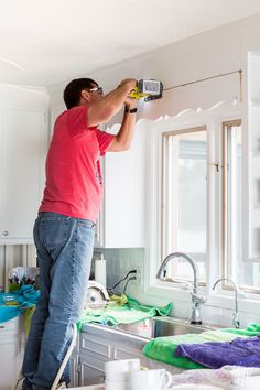 a man is painting the ceiling in his kitchen