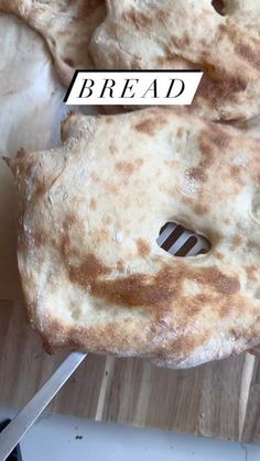 bread is sitting on top of a cutting board next to a knife and some scissors