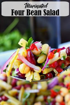 a close up of a spoon full of food with the words marinated four bean salad on it