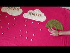 a child's hand is reaching out to make a cloud and rain scene on a pink blanket