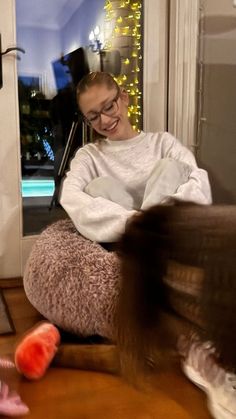 a woman sitting on top of a chair next to a cat and a toy mouse