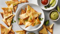 tortilla chips with guacamole and salsa on white plate next to small bowls