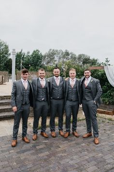 a group of men standing next to each other on top of a brick floor covered ground