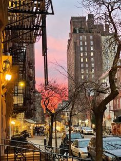 a city street filled with lots of traffic next to tall buildings at sunset or dawn