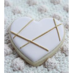 a white heart shaped cookie with gold sticks in it's center on a crocheted blanket