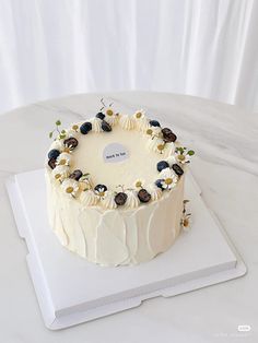 a white cake sitting on top of a cutting board covered in frosting and flowers