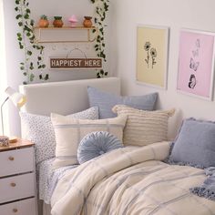 a bed with blue and white comforters in a bedroom next to a wall with pictures on it