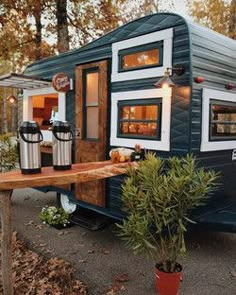 a small blue and white trailer parked on the side of a road next to trees