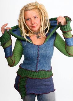 a woman with blonde hair wearing a blue sweater and green scarf over her shoulders, posing for the camera