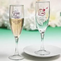 two wine glasses sitting on top of a white plate next to each other with love written on them