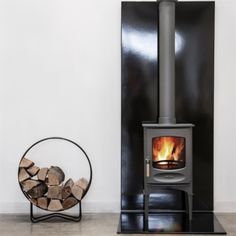 a wood burning stove sitting next to a stack of logs