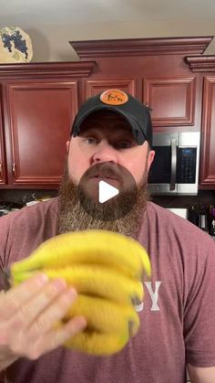 a man with a beard holding a bunch of bananas in his hand and looking at the camera