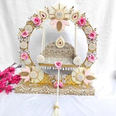 an elaborately decorated carousel with flowers and pearls on the sides, sits in front of a white backdrop