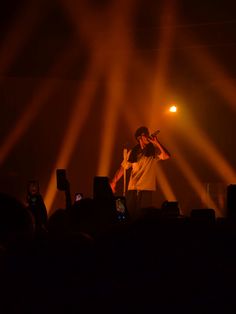 a man standing on top of a stage holding a microphone in his hand and lights behind him