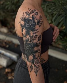 a woman with a black and white flower tattoo on her arm, looking at the camera