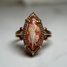 Beautiful marquise shaped cameo ring carved of natural sardonyx showing a figure of a woman in a dress. Yellow gold decorative border and setting.  Preloved item, previously resized, evidence of this can be seen on the band. Wiggles slightly in setting. Size (approx.): 7.75 US Stamped SIFFARI 10KT Weight: 2.818g **FREE shipping within Canada and USA** If you have any questions or concerns, please do not hesitate to contact us. We will be more than happy to help you and answer any inquiries.  We Cameo Rings For Sale, Antique Cameo Ring Collectible, Antique Carved Collectible Ring, Vintage Cameo Rings For Collectors, Victorian Oval Carved Rings, Vintage Cameo Ring With Oval Cabochon, Vintage Cameo Oval Cabochon Rings, Antique Cameo Ring Jewelry, Victorian Carved Rings Ideal For Gifts