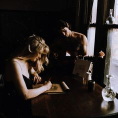 two people sitting at a table writing on paper