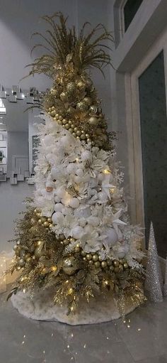 a white christmas tree decorated with gold ornaments