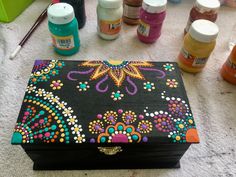 a painted box sitting on top of a table next to other paint bottles and supplies