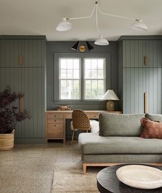 a living room filled with furniture and lots of green painted wood paneling on the walls