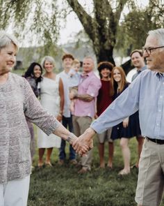 an older couple holding hands in front of a group of people