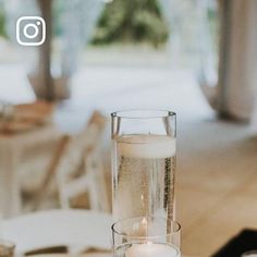 a table topped with a glass vase filled with water and candles