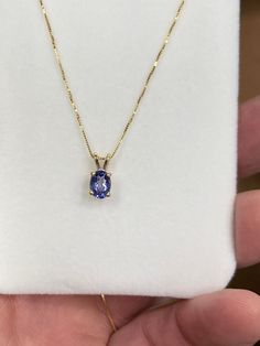 The item is a 14k yellow gold tanzanite pendant and chain. The pendant has four prongs holding in the 7 x 5 millimeter oval tanzanite. The tanzanite weighs 0.85 carats. The box chain is also made of 14k yellow gold. The chain measures 18 inches in length and has a lobster claw catch on the end. We will provide a pendant box. Luxury Purple Tanzanite Necklace, Classic Oval Tanzanite Necklaces, Classic Oval Tanzanite Necklace, Yellow Gold Tanzanite Oval Necklace, Fine Tanzanite Oval Pendant Jewelry, Gold Tanzanite Oval Jewelry, Tanzanite Pendant, Tanzanite Necklace, Crystal Figurines