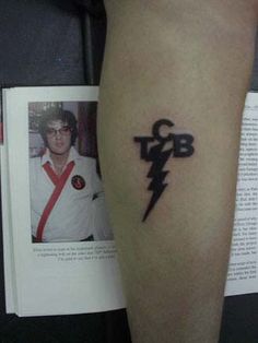 a man with a lightning bolt tattoo on his left arm, next to an open book