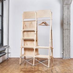 a wooden shelf with clothes on it in an empty room