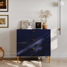 a blue cabinet with pictures on the wall behind it and a vase next to it