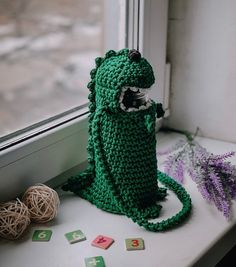 a green crocheted toy sitting on top of a window sill