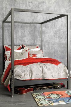 a bed with red and white pillows on it, next to a carpeted floor