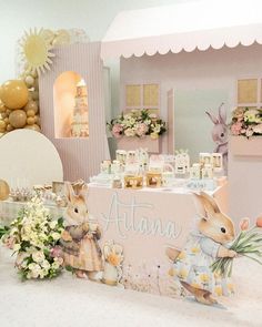 a table topped with lots of decorations and bunnies next to a pink tent covered in flowers