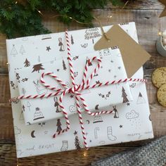 a wrapped present sitting on top of a wooden table next to cookies and crackers