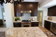 a kitchen with marble counter tops and dark wood cabinets