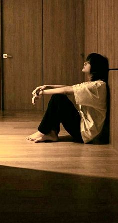 a woman sitting on the floor in front of a wooden door with her arms outstretched