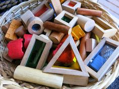 a basket filled with lots of different colored wooden shapes and sizes on top of a table