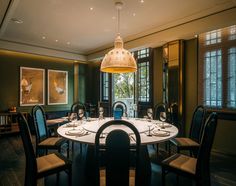 a dinning room table set with place settings for four and wine glasses on it