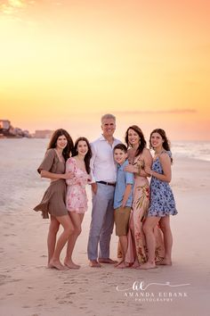 a family poses on the beach at sunset