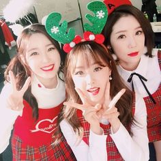 three girls dressed in christmas costumes posing for the camera with their hands up and making peace signs