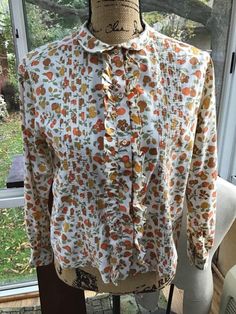 "Vintage 1960s ladies blouse. Cotton blend. Buttons down the front with ruffly fabric and Pin tucking along the sides. The design on the blouse are of Fruit and Pine Cones. The brand label is: *Laura Mae Life Blouse Washes Like A Hanky*. NO fading to the colors on the blouse. (Sunlight during photography may make it appear as such). Has been freshly laundered and ironed. CONDITION: No issues noted. SIZE TAG READS: 38 BUT PLEASE go by the measurements I provide below. I do not accept returns and Vintage Ruffles Blouse For Daywear, Vintage Ruffled Blouse For Daywear, Retro Blouse With Peter Pan Collar For Vintage Fashion, Retro Blouse With Peter Pan Collar, Retro Ruffled Blouse For Fall, Vintage Tie Neck Blouse For Fall, Retro Blouse With Peter Pan Collar For Daywear, Fall Vintage Blouse With Vintage Pattern, Vintage Tops With Ruffled Collar