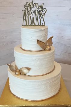 a three tiered white wedding cake with gold decorations on top and the words, after all this time alwayss