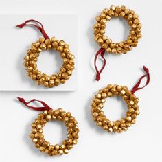 three gold beaded wreaths with red ribbon on white surface, one is empty and the other two are closed