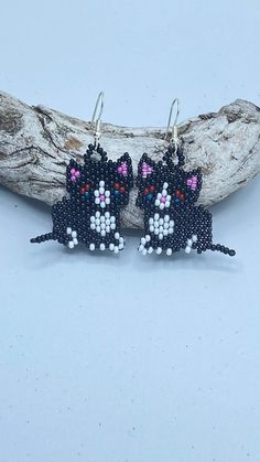 black and white cat beaded earrings sitting on top of a piece of wood