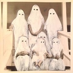 an old photo of five people dressed in white ghost costumes sitting on steps with their heads down